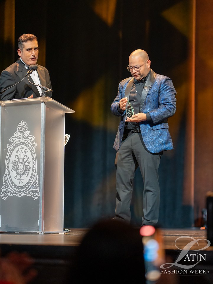 An award recipient in a blue jacket stands beside the presenter at the podium