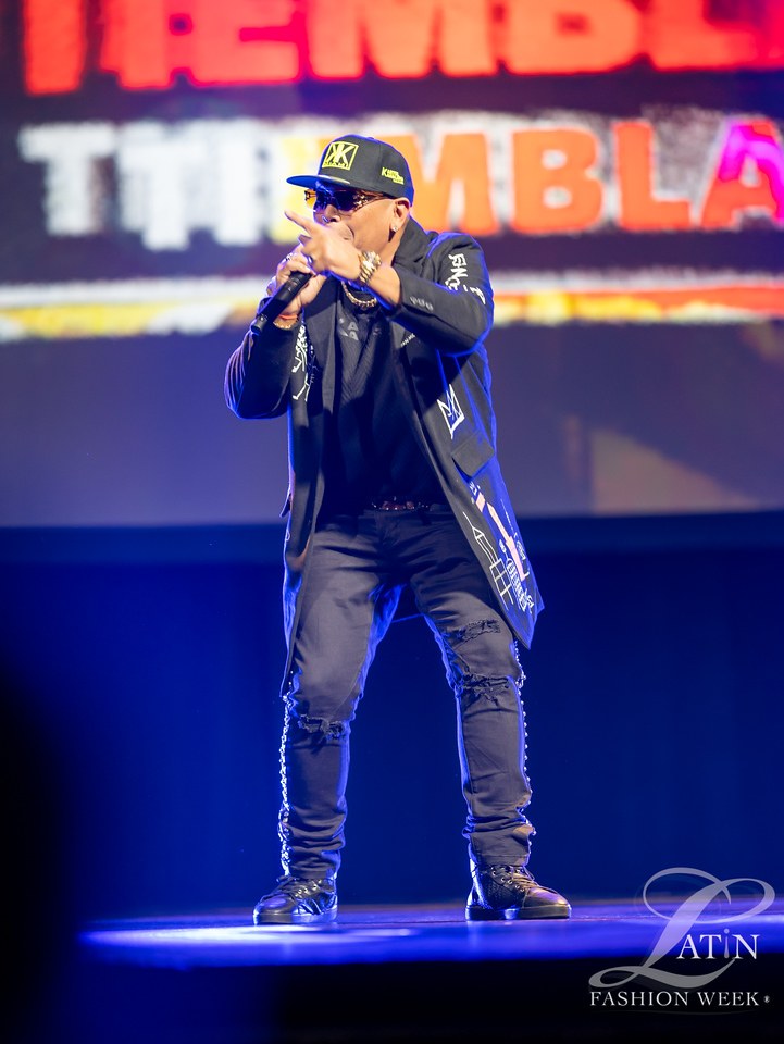 A musician performs onstage under blue lighting