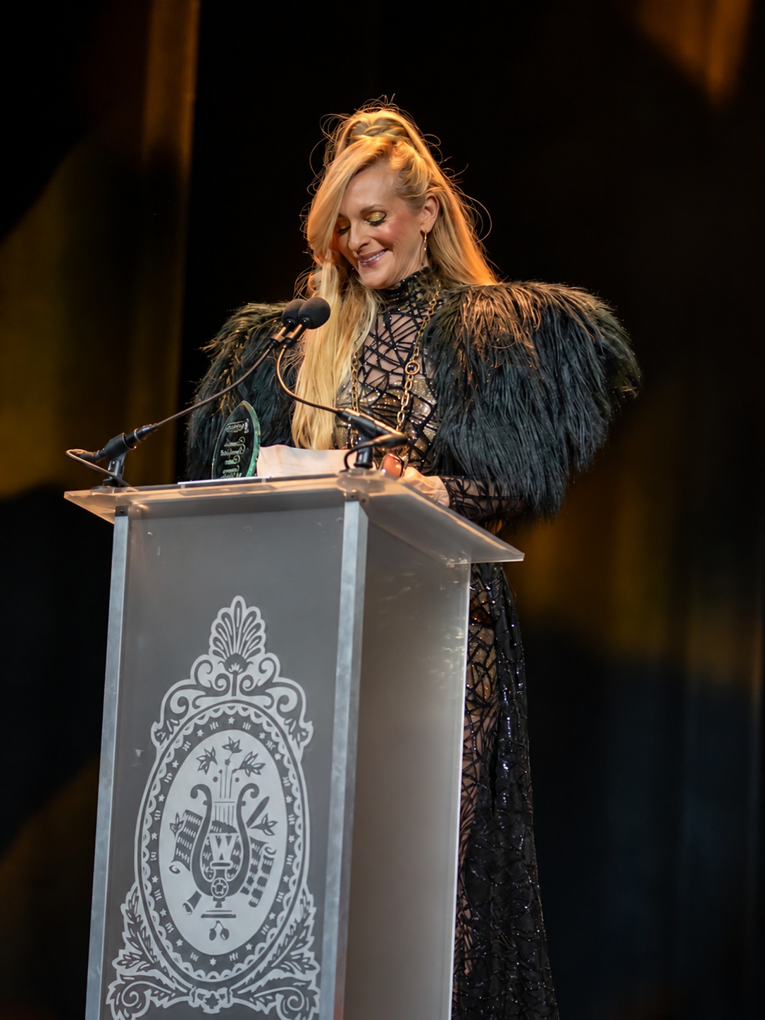 Consuelo Vanderbilt Costin speaking at the Latin Fashion Awards podium with her award